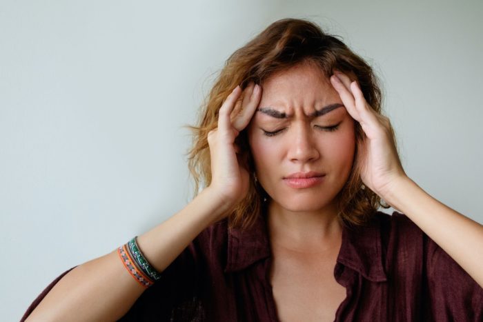 young woman in pain holding her head headaches dentist in Chapel Hill North Carolina